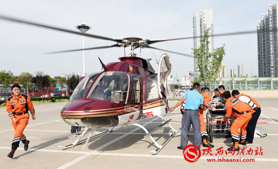 穿橙色衣服的航空救援队，将患者安全护送至直升机，转往医院进一步救治。记者 杨大君 摄